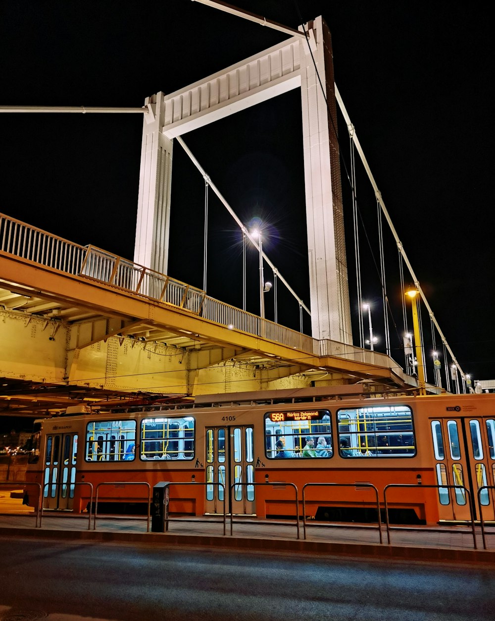 orange and white train under bridge during night time