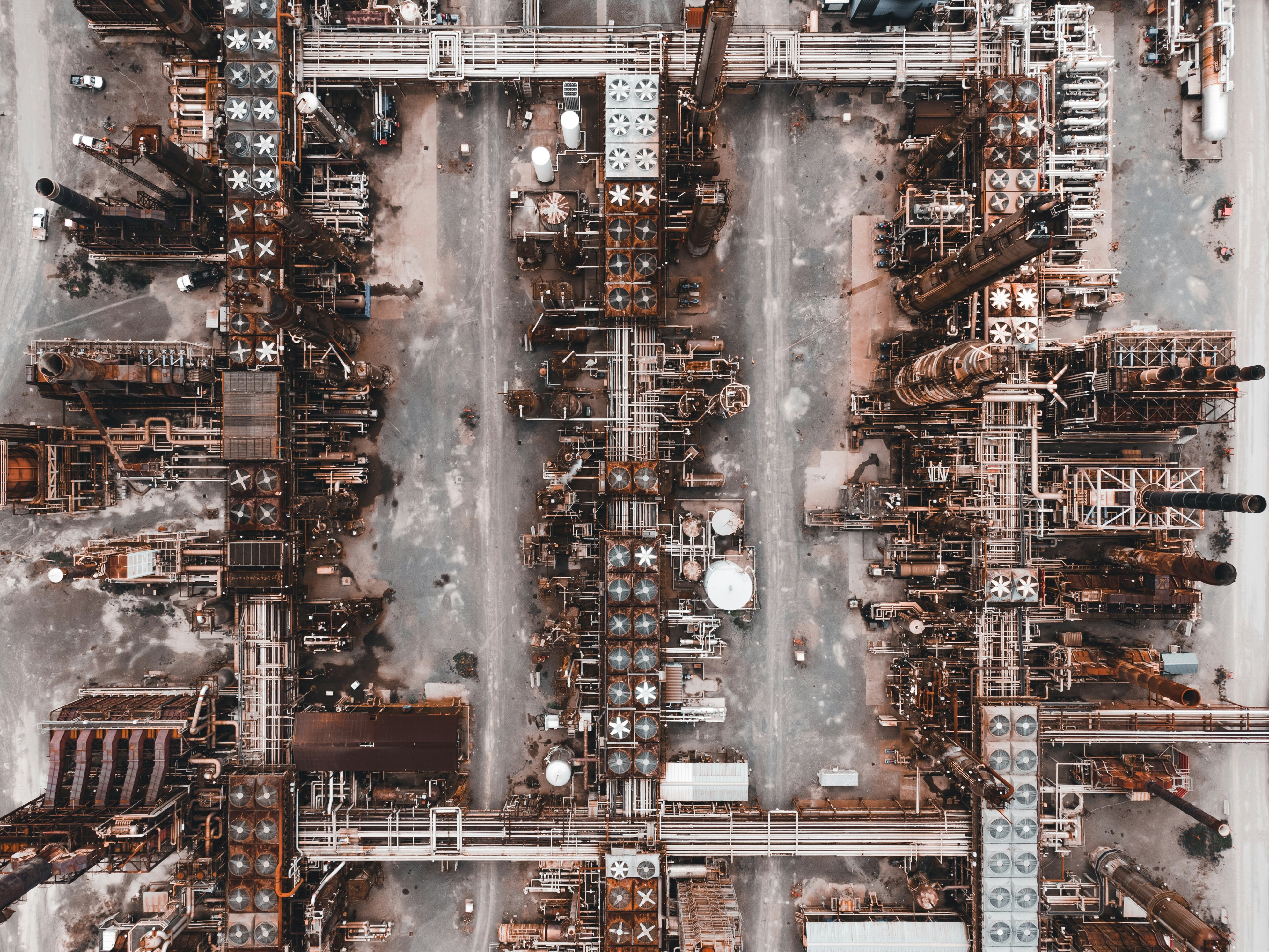 An aerial view of a massive oil refinery with pipes and storage tanks, symbolizing energy production and supply chain