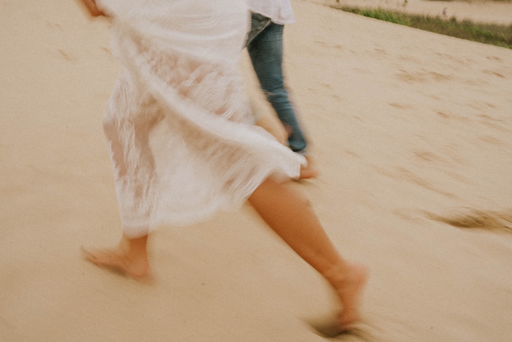 woman in white dress walking on sand during daytime