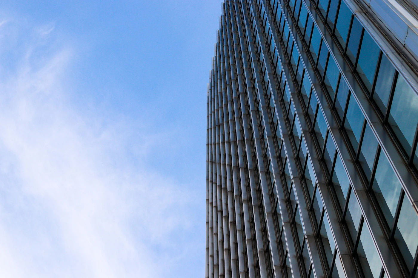 Helles blaues Glas-Hochhaus vor freundlichem Himmel