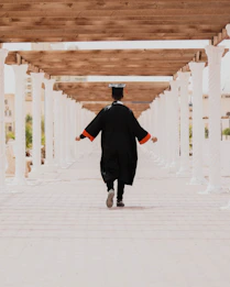 man in black long sleeve shirt and black pants walking on white concrete pathway