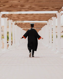 man in black long sleeve shirt and black pants walking on white concrete pathway