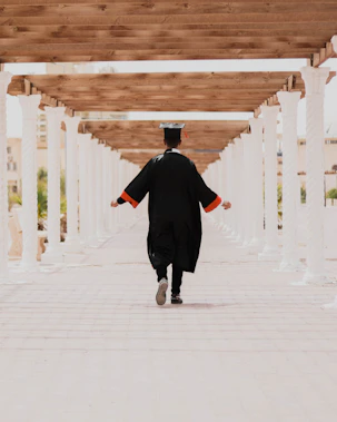 man in black long sleeve shirt and black pants walking on white concrete pathway