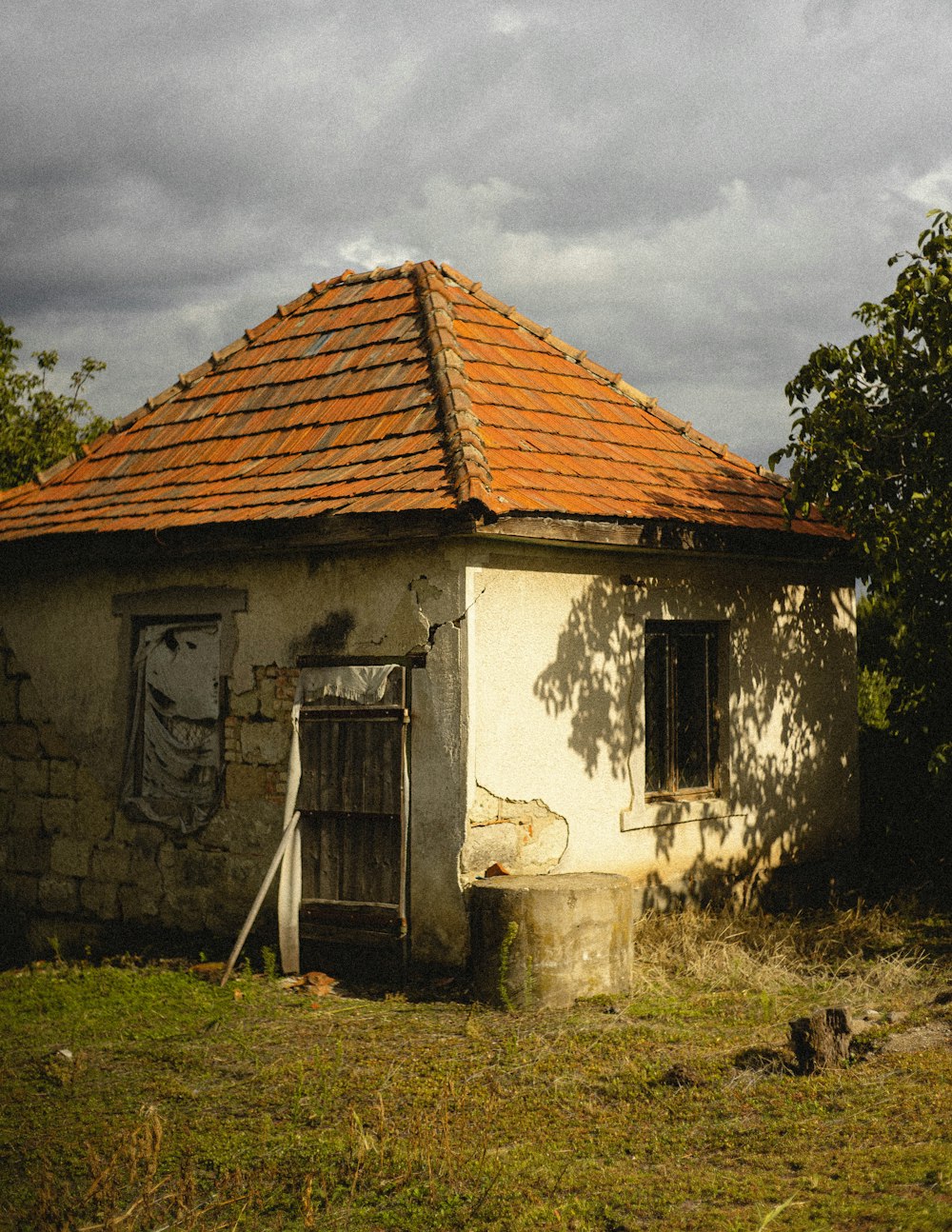 white and brown concrete house near green trees under white clouds and blue sky during daytime