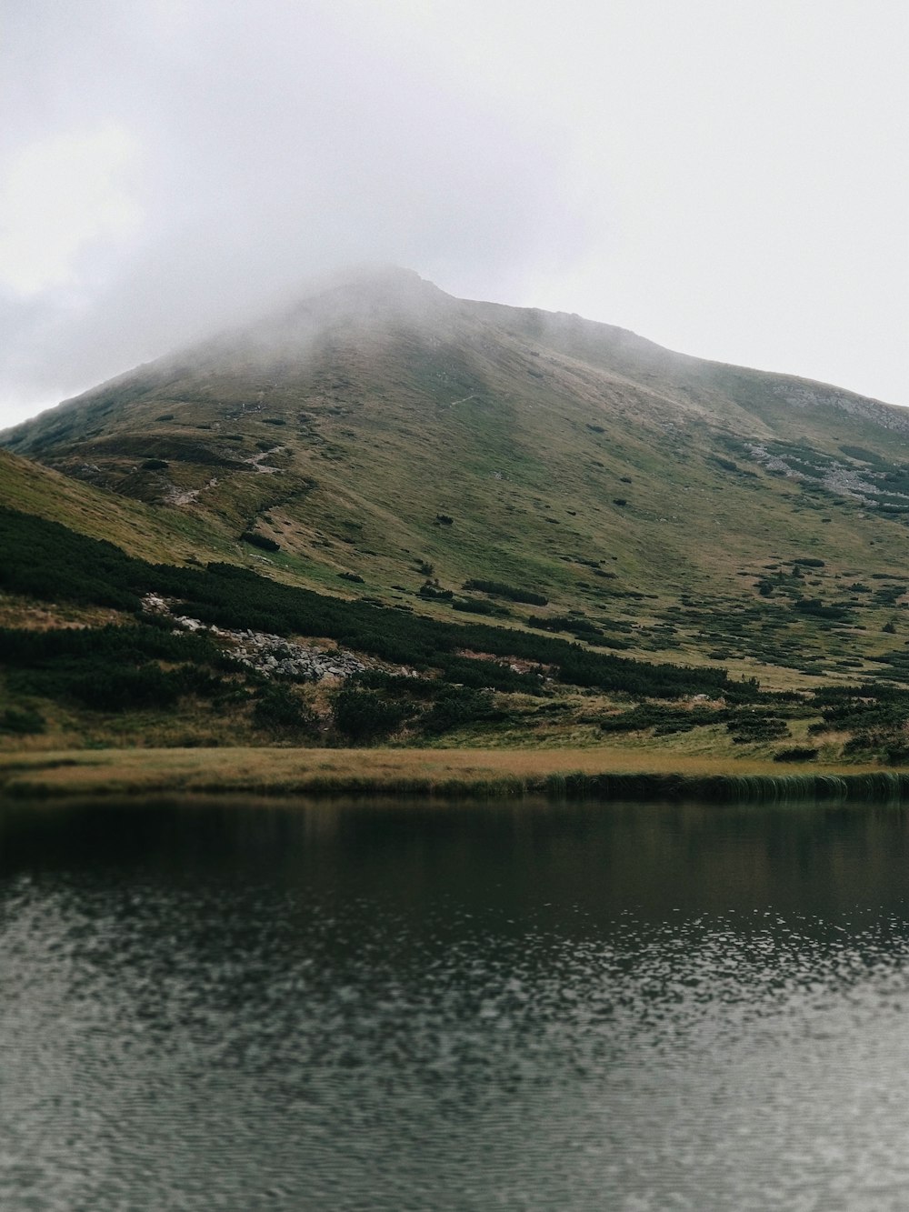 Montaña verde y marrón junto al lago