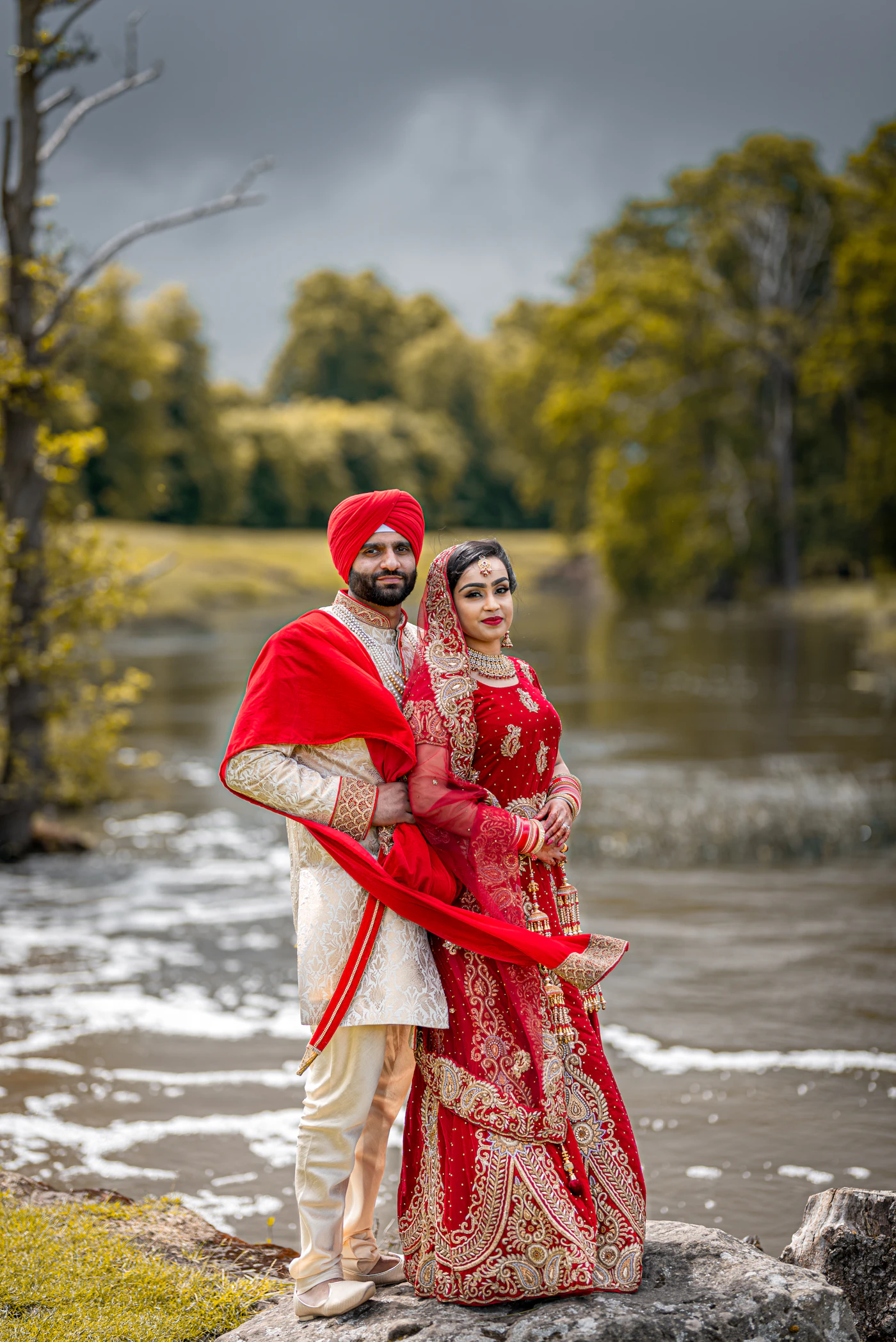 Couple in traditional attire photographed on a rock beside a river