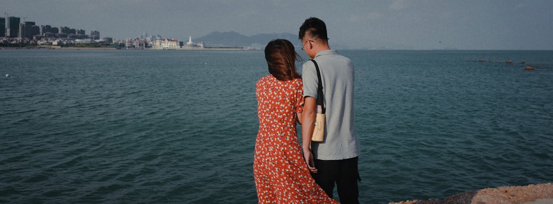 man and woman standing beside each other near body of water during daytime