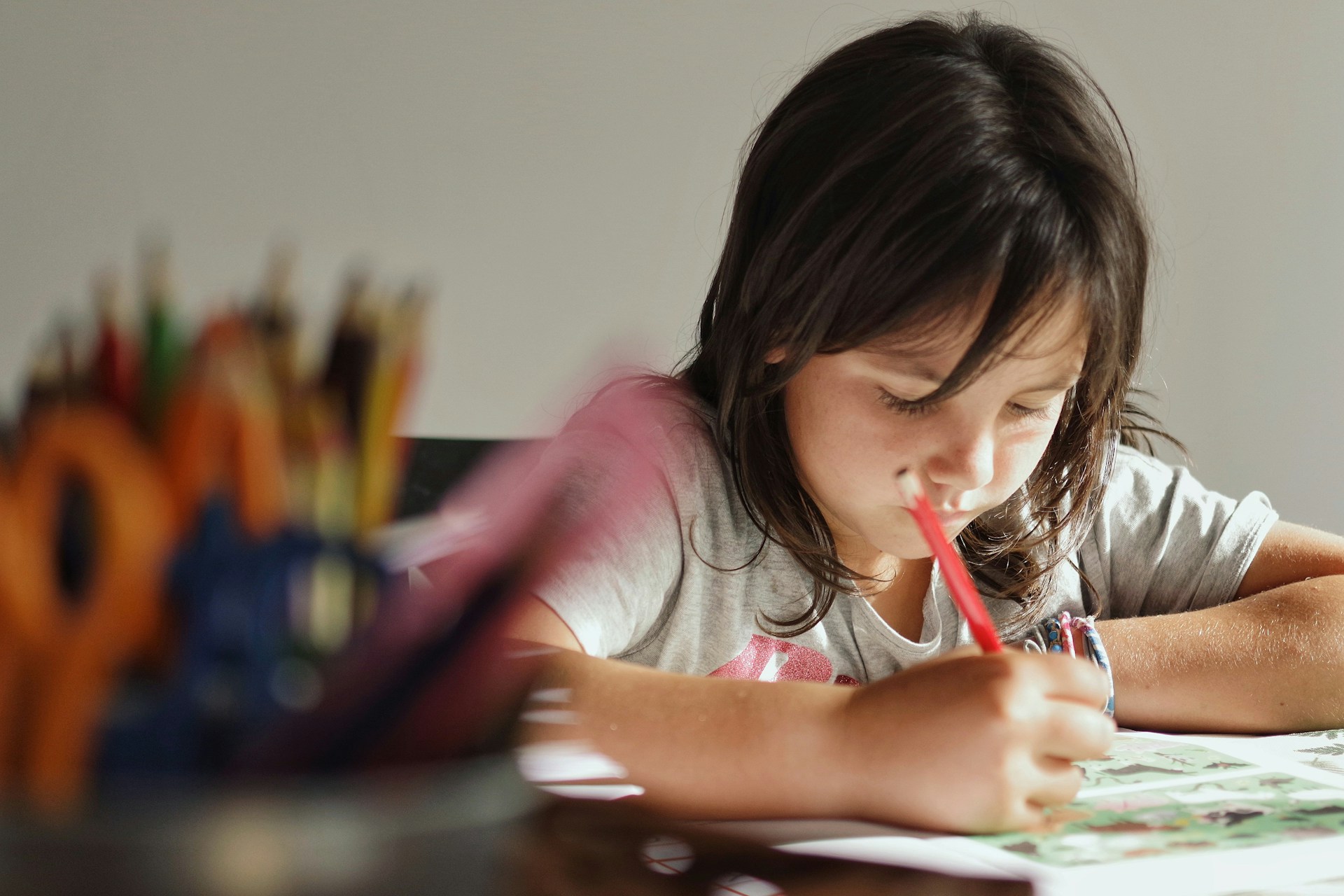 girl in pink t-shirt writing on white paper