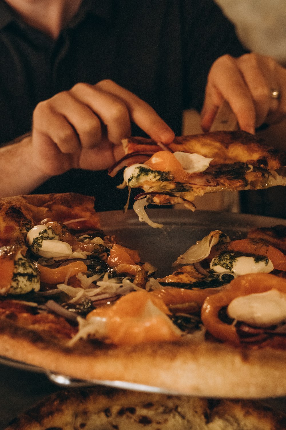 person holding pizza with cheese and sauce