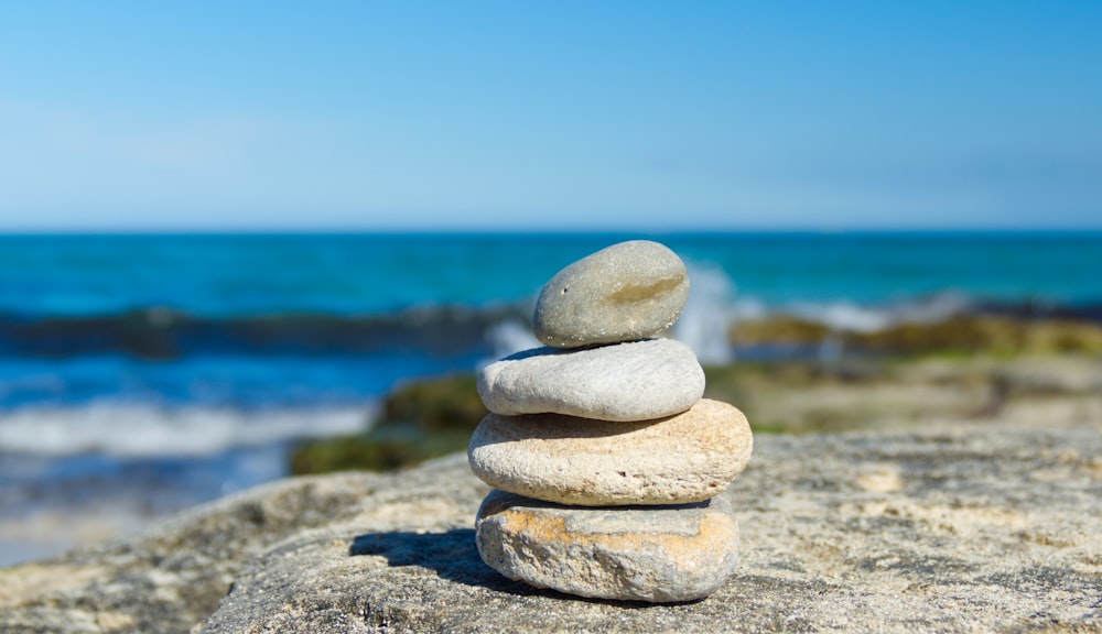 stack of gray and white stones on gray sand near body of water during daytime