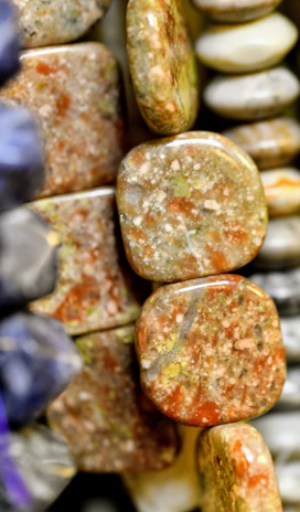 A close-up of a cluster of polished unakite stones showing their green and pink hues.