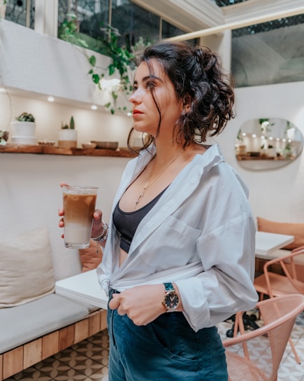A stylish woman wearing a chic outfit while sipping coffee in a cozy café.