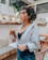 A smiling young woman enjoying a cold iced coffee in a modern cafe setting.