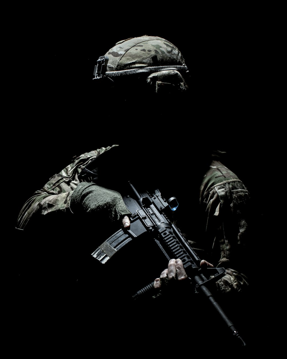 homme en costume de camouflage noir et vert tenant un fusil