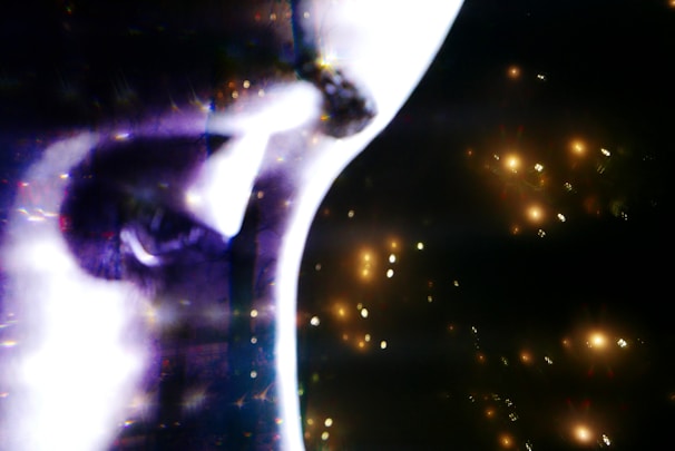 Close-up of Elara's face with dramatic gold accents highlighting her features against a dark, moody background.