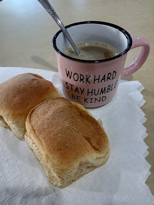 A latte beige mug with confident typography sitting next to a vintage chalkboard with motivational quotes in a cozy coffee nook