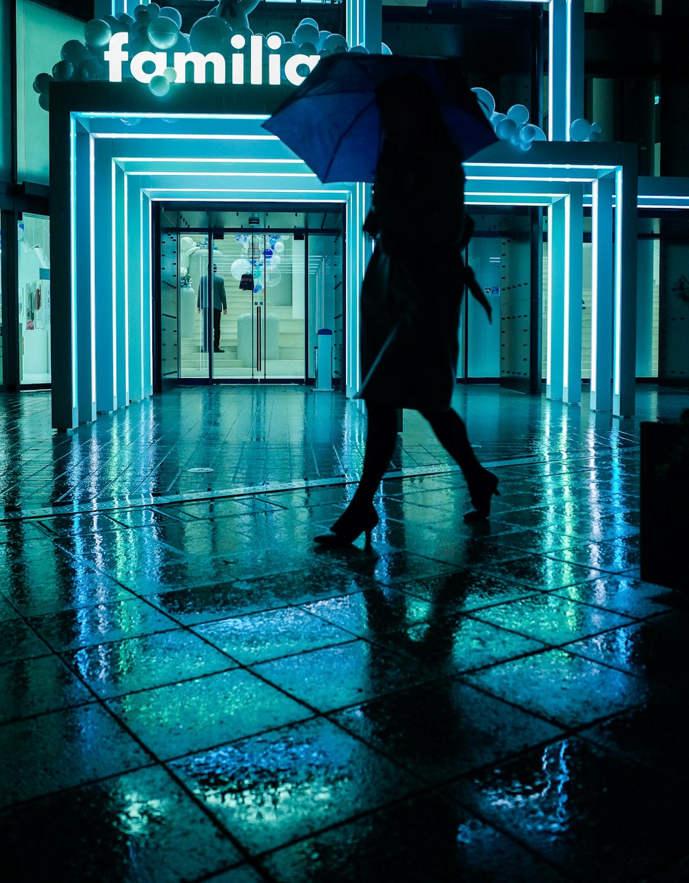 woman in black jacket and pants walking on blue floor tiles