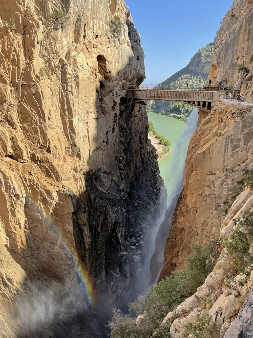 bridge over river between rocky mountain during daytime