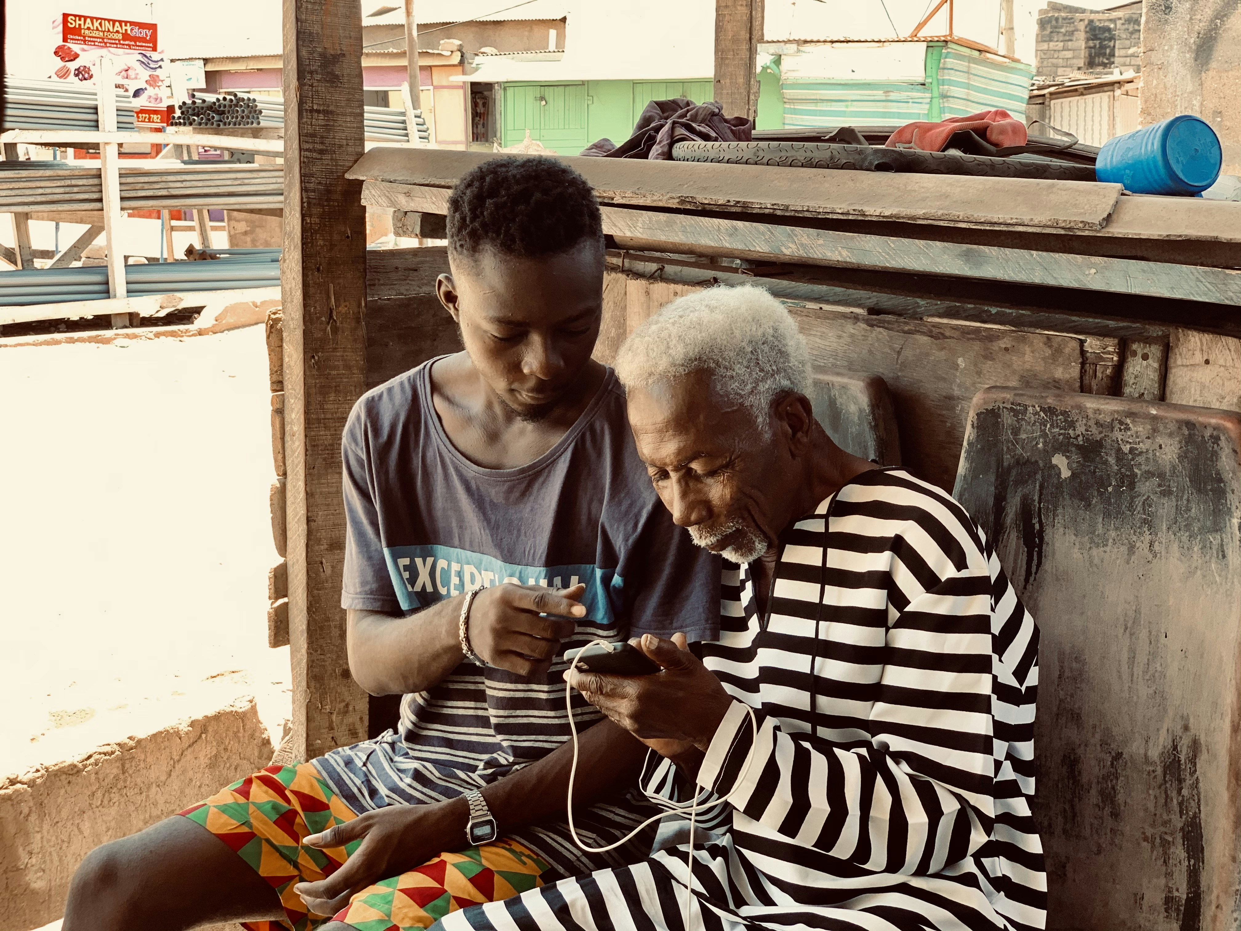 An older woman guides a child's hands as they hold knitting needles together