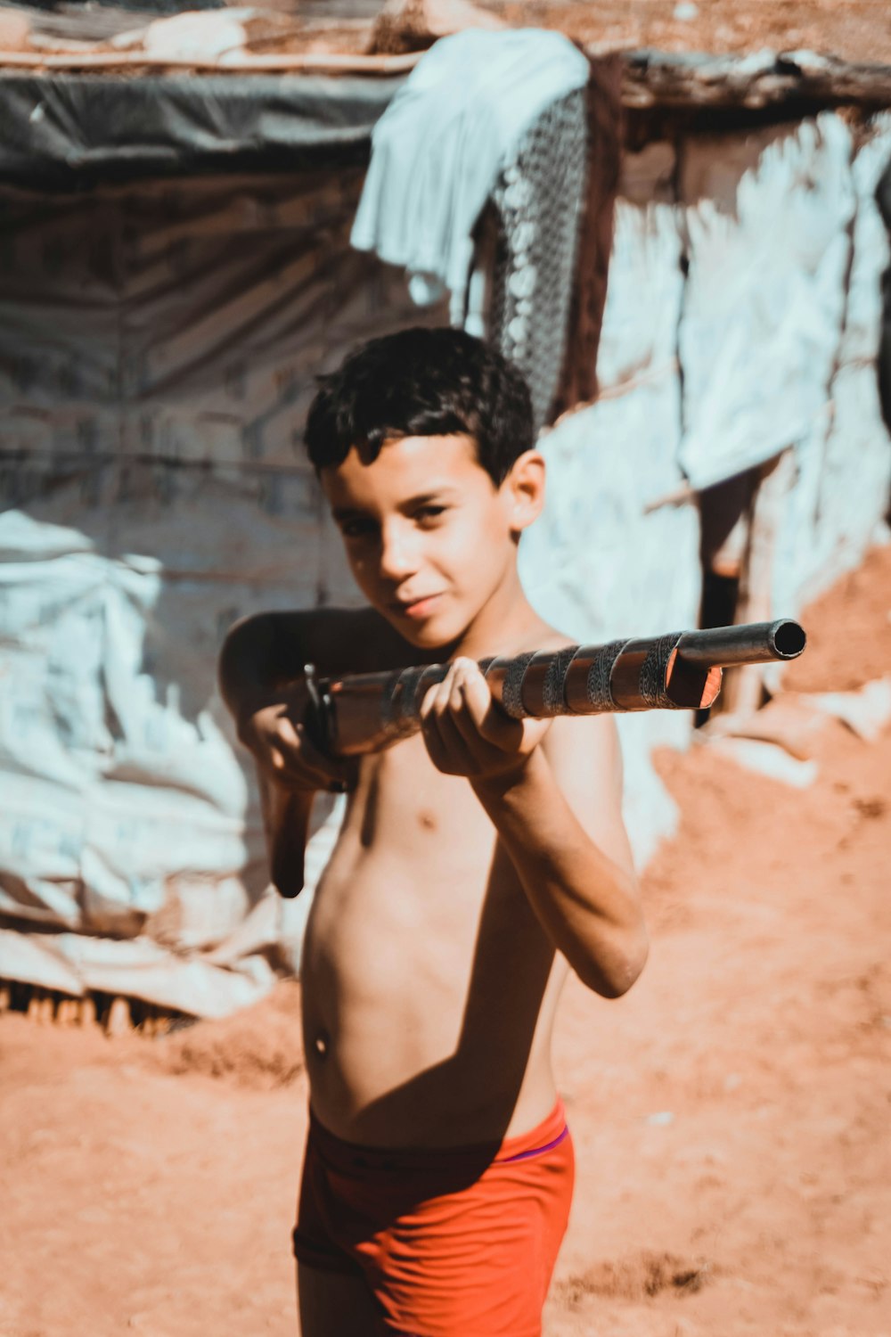 topless man holding black and brown rifle