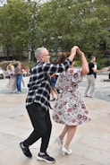 Happy couple dancing with guests enjoying music at a backyard party