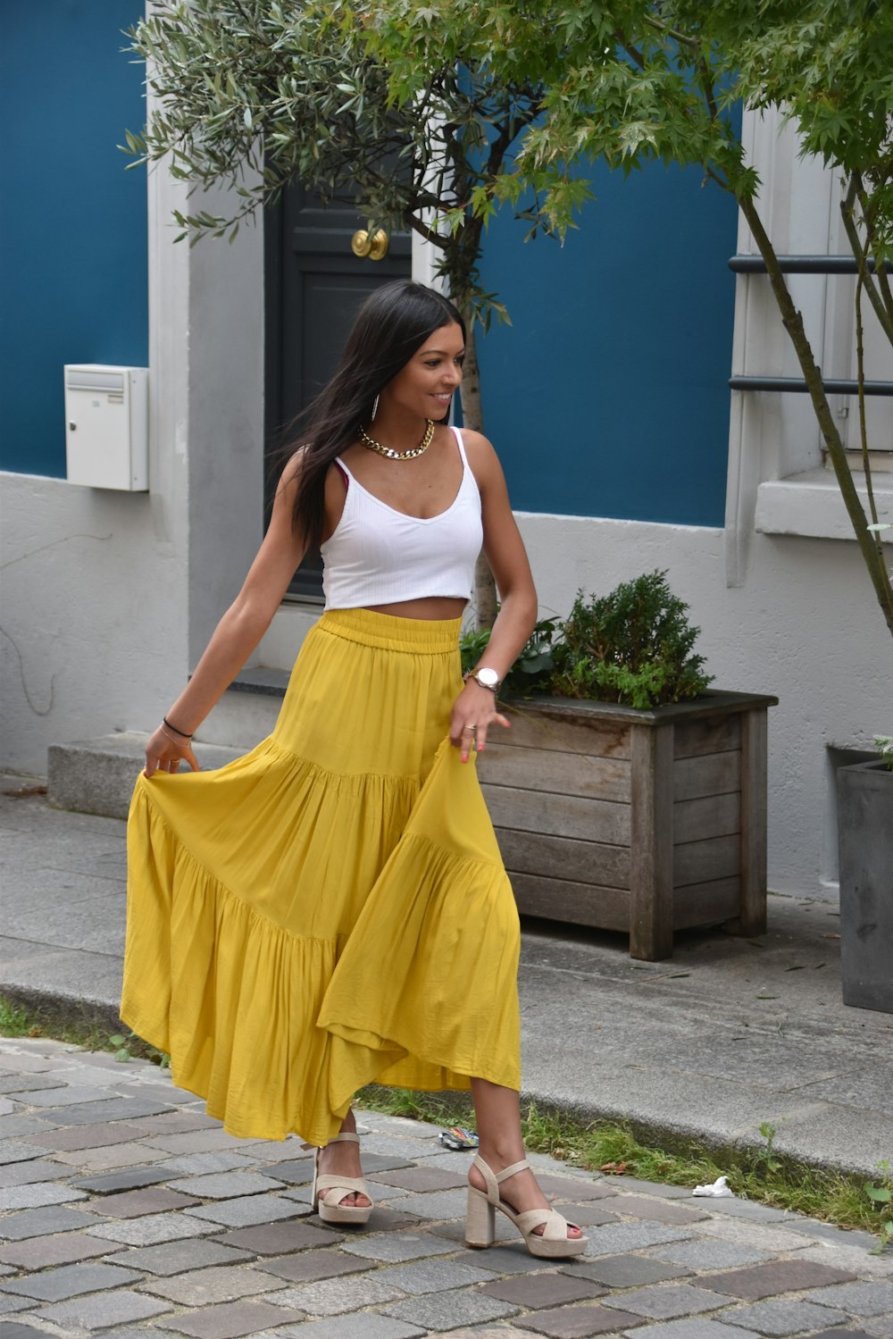 Woman in white tank top and yellow skirt standing on gray concrete floor  during daytime photo – Free Rue crémieux Image on Unsplash