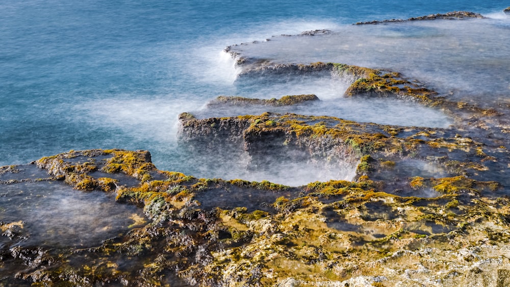 brown and black rock formation near body of water during daytime