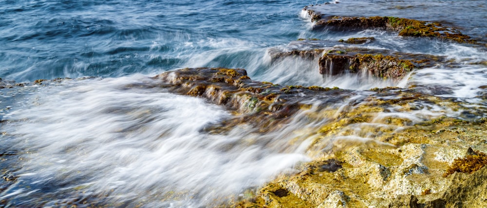 water waves hitting rocks during daytime