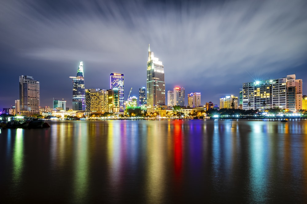 city skyline across body of water during night time