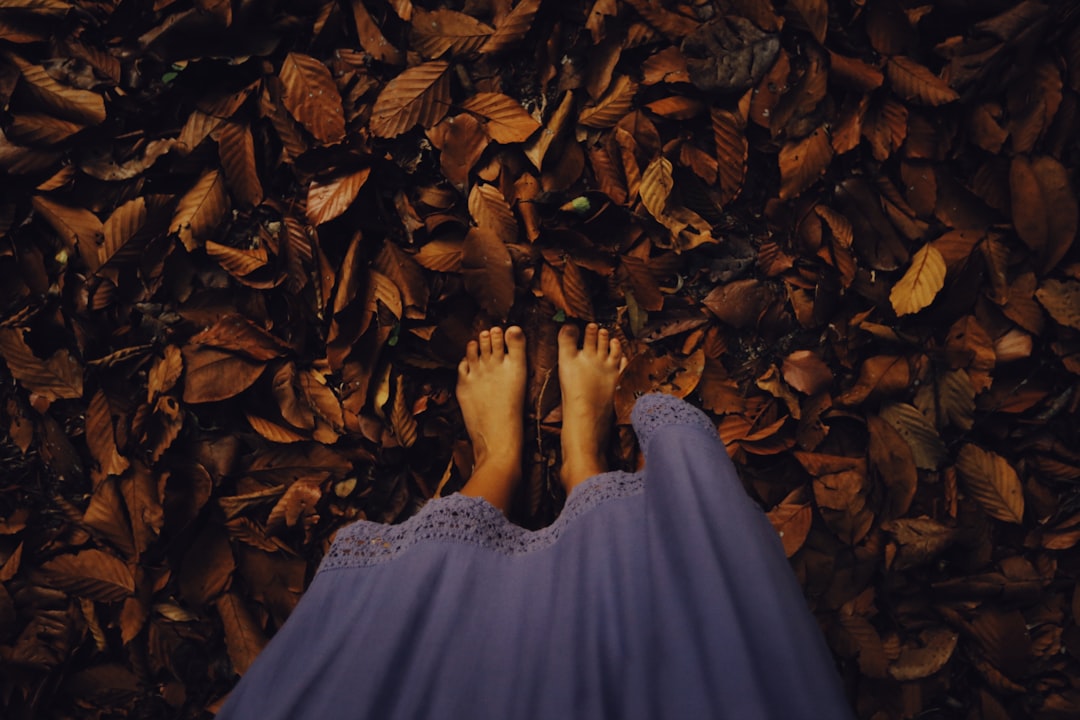 woman in white dress standing on dried leaves
