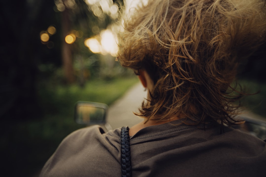 woman in black jacket standing near green car during daytime