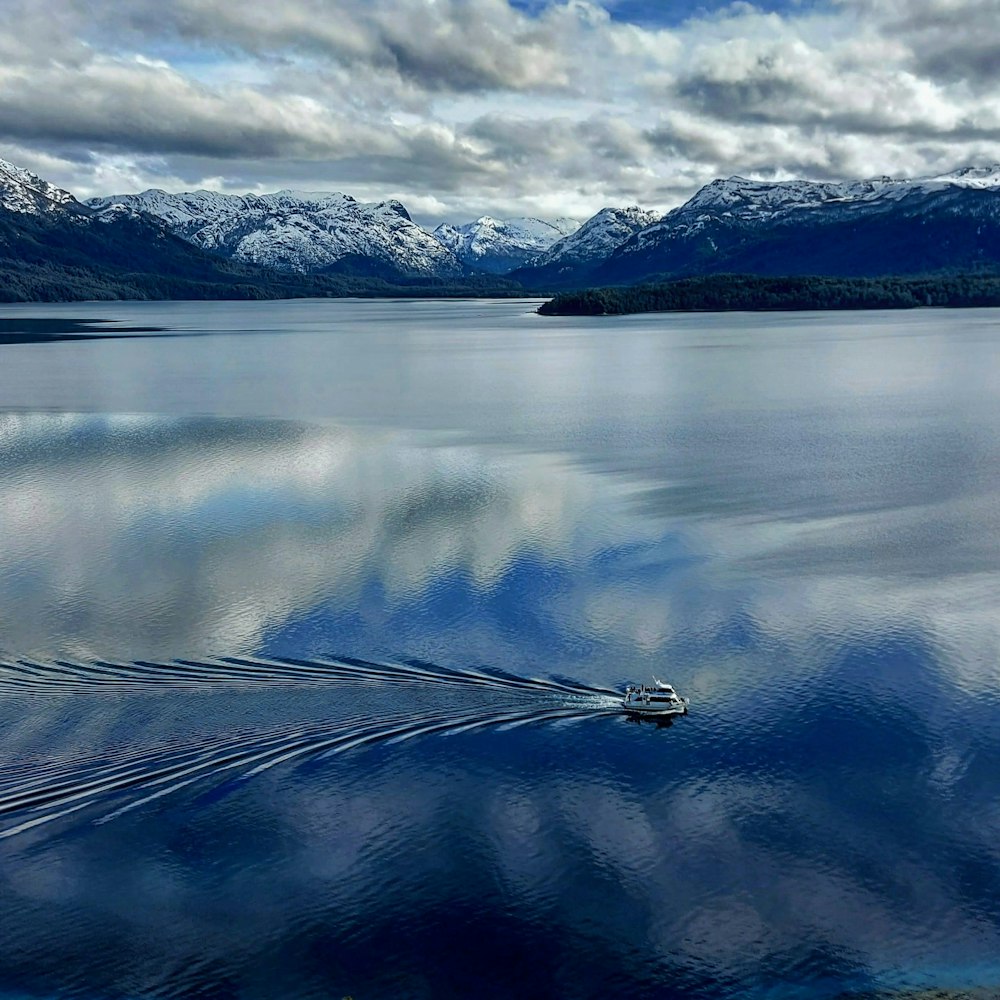 body of water near mountain under white clouds during daytime