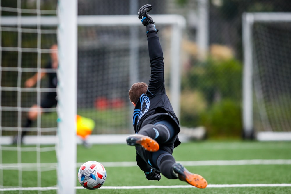 man in black and white jersey shirt playing soccer during daytime