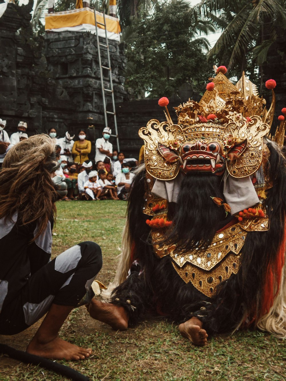 people in gold and red floral headdress sitting on green grass field during daytime