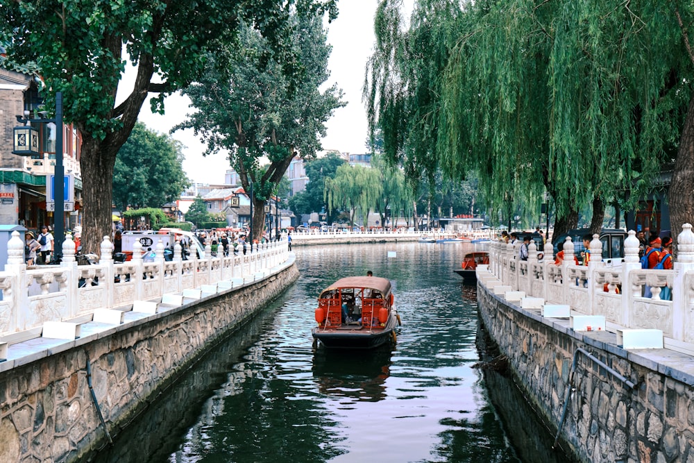 people walking on sidewalk near river with boats during daytime