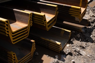 A close-up of sturdy steel beams stacked neatly at a construction site under a clear sky.