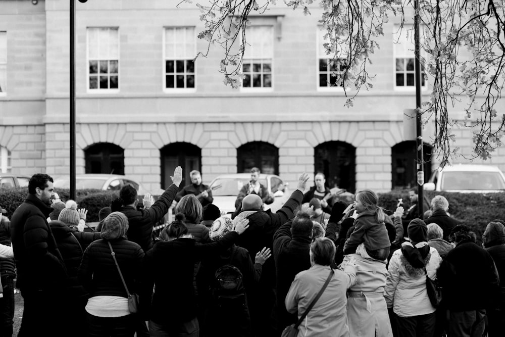 Foto en escala de grises de personas de pie cerca de un edificio
