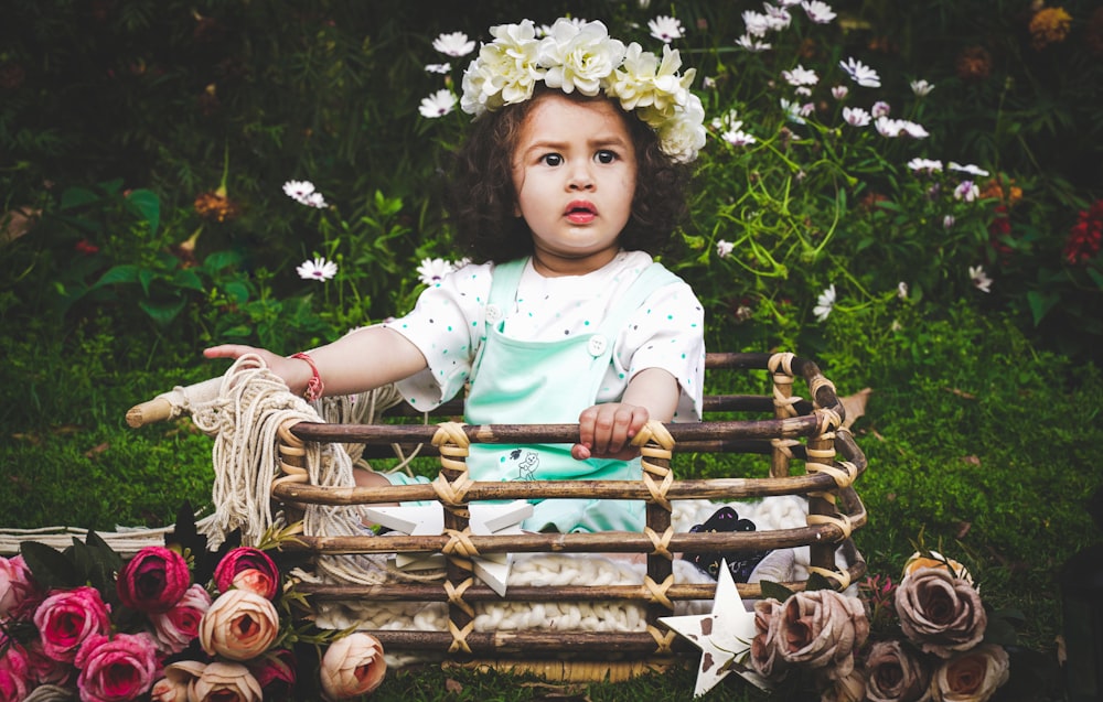 girl in white and pink floral dress lying on brown wooden swing bench