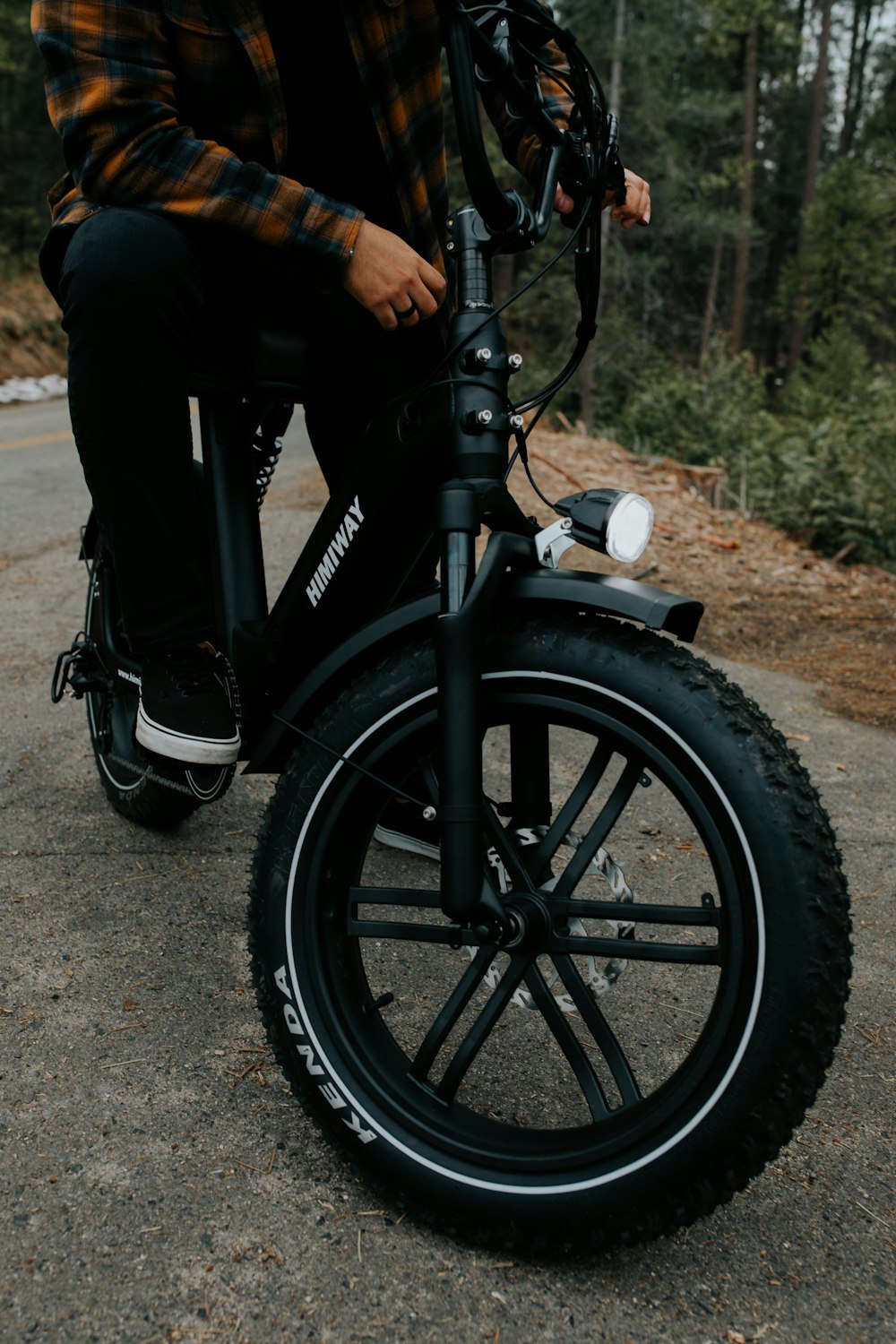 person riding black bicycle on gray concrete road during daytime