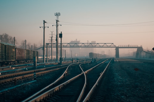 Close-up of railway tracks with heavy freight trains passing through an industrial landscape.