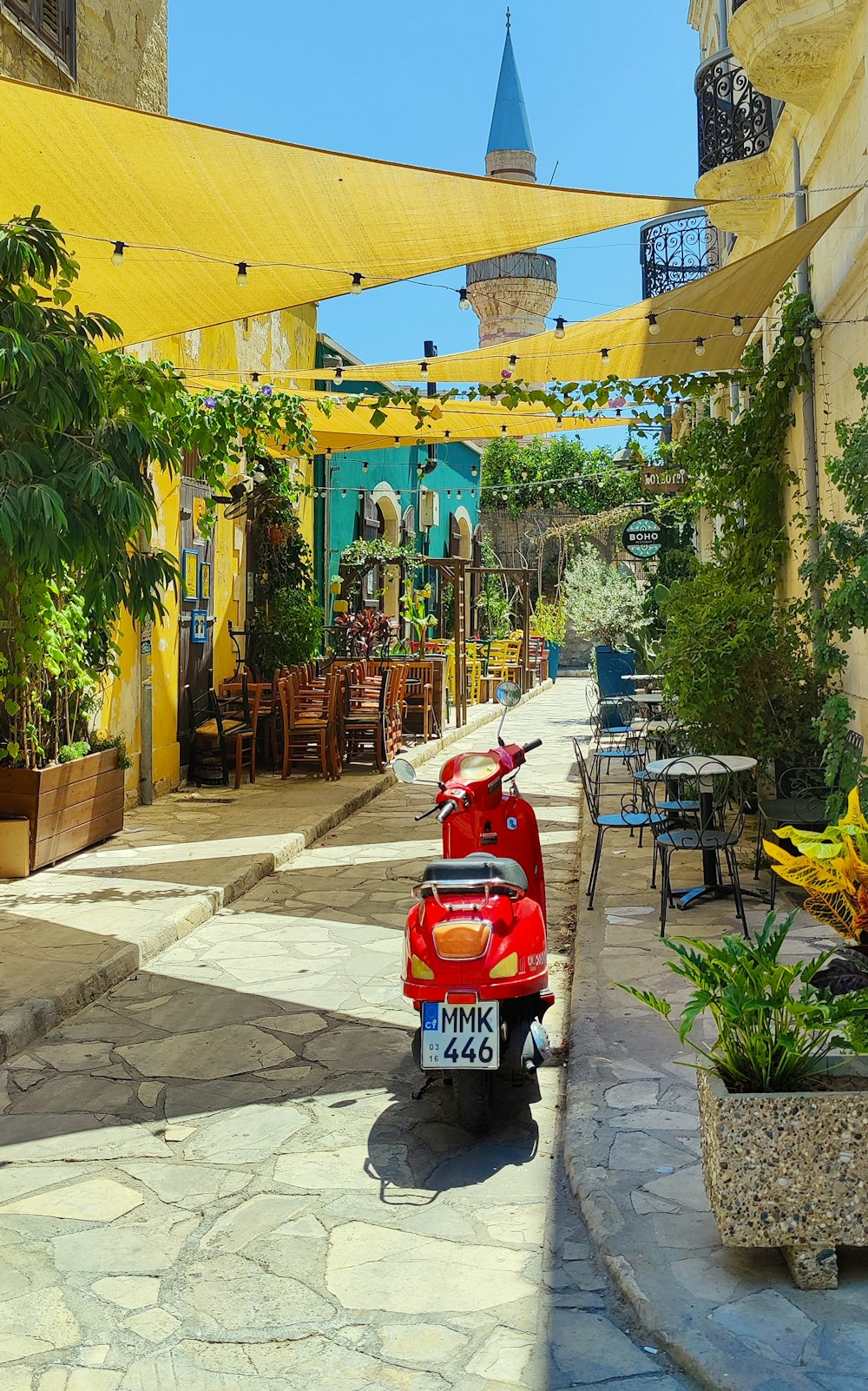 red motor scooter parked near yellow and blue concrete building during daytime