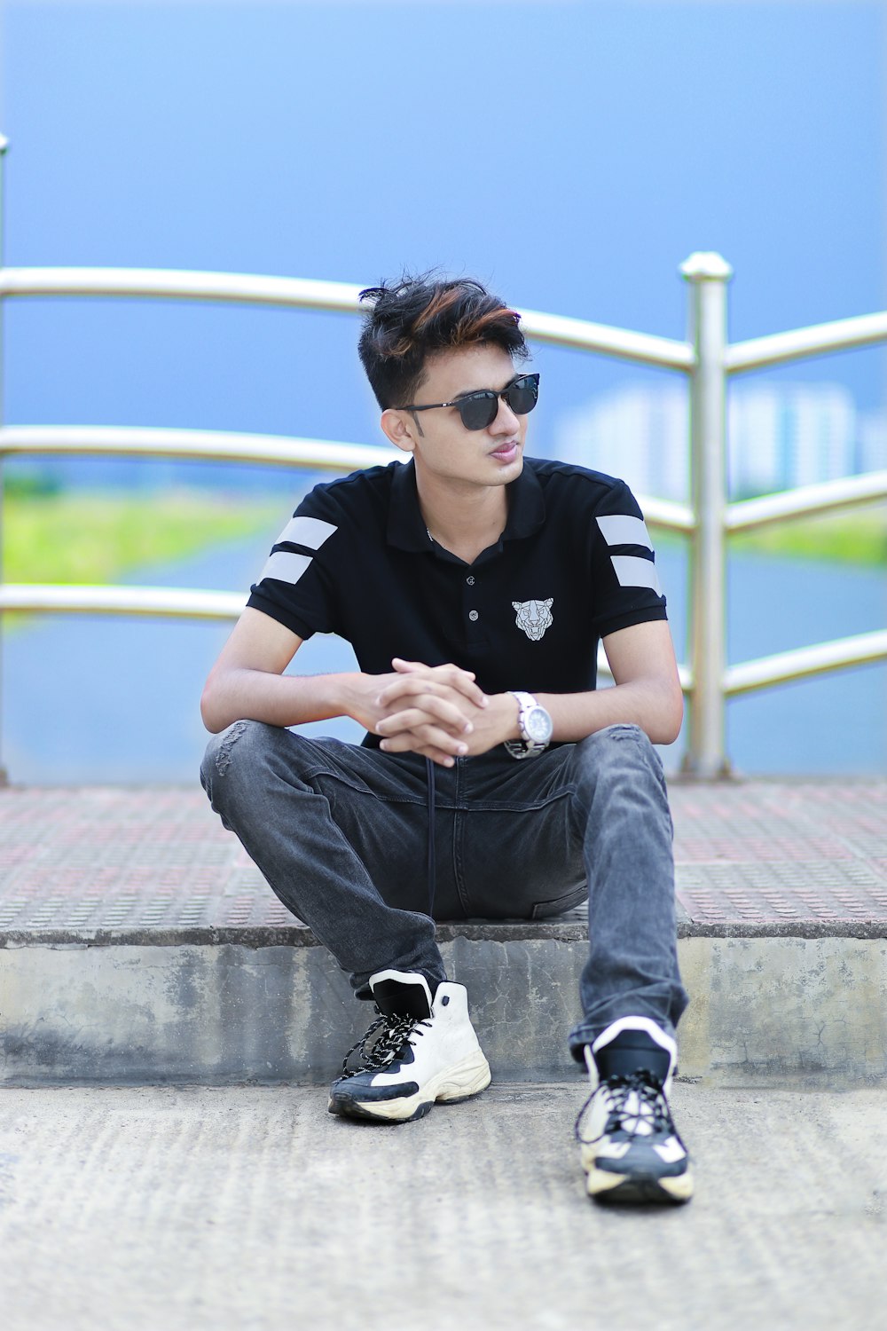 man in black and white stripe polo shirt and blue denim jeans sitting on concrete floor