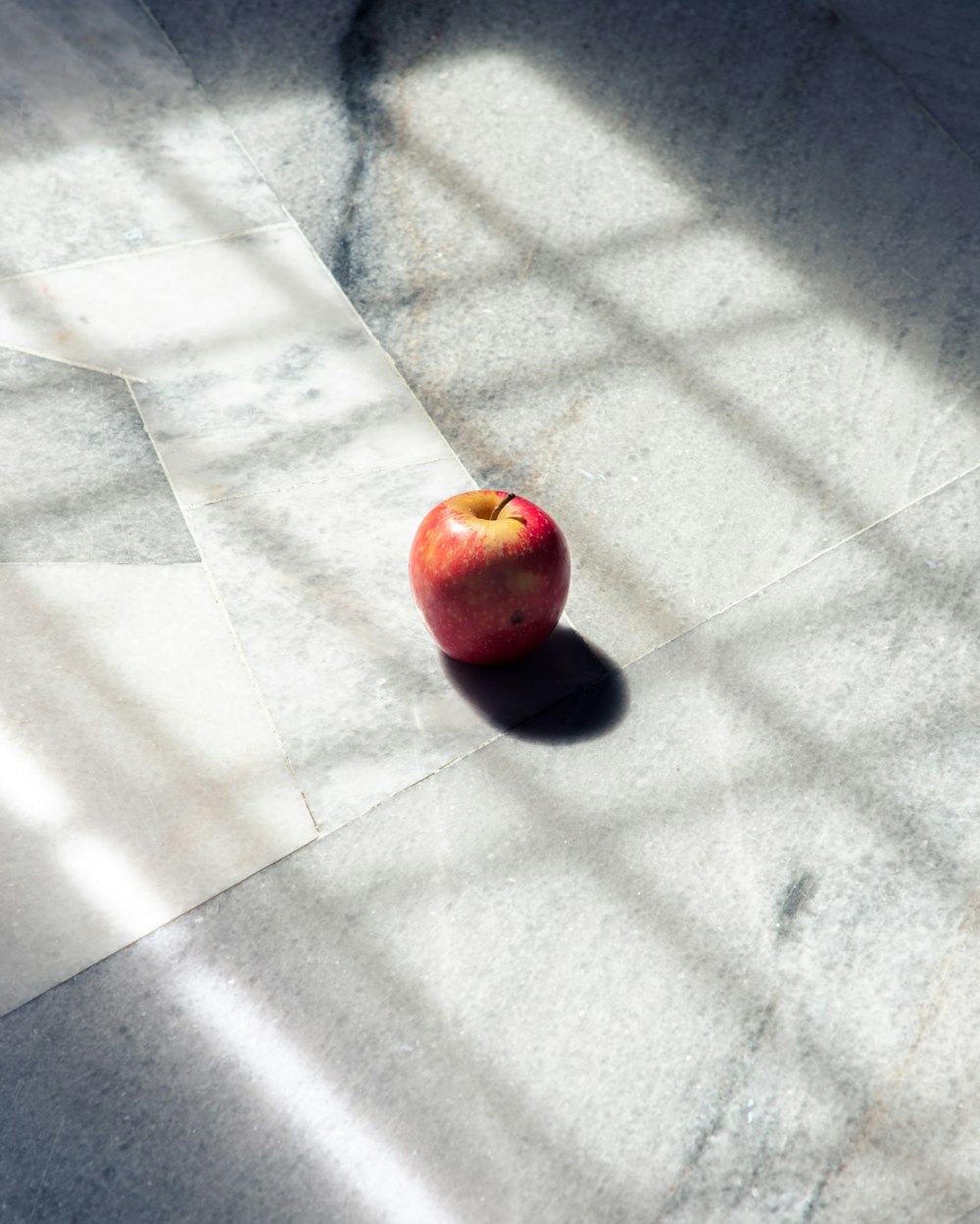 red apple fruit on white floor tiles