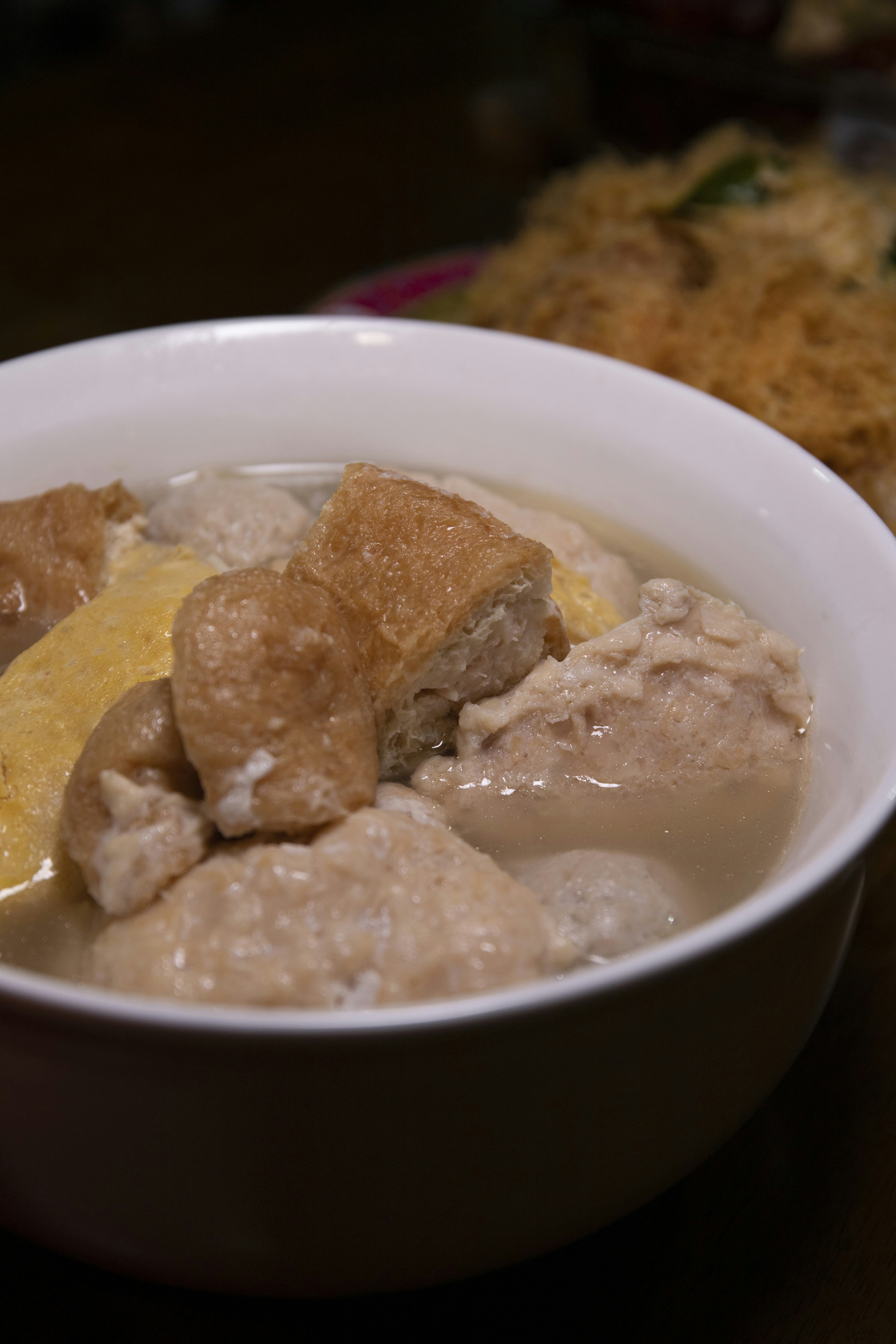 White fufu ball in a bowl of light soup with goat meat and red pepper broth