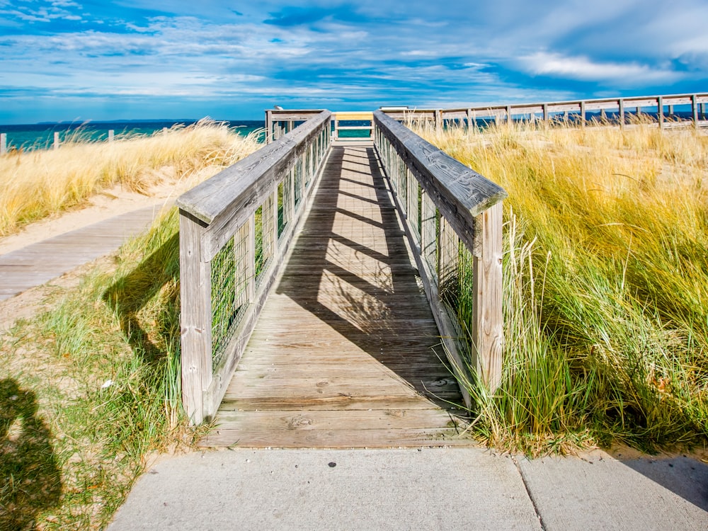 brown wooden bridge on brown grass field under blue sky during daytime