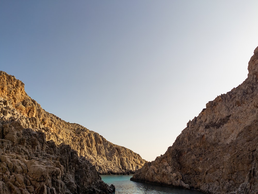 brown rocky mountain beside body of water during daytime