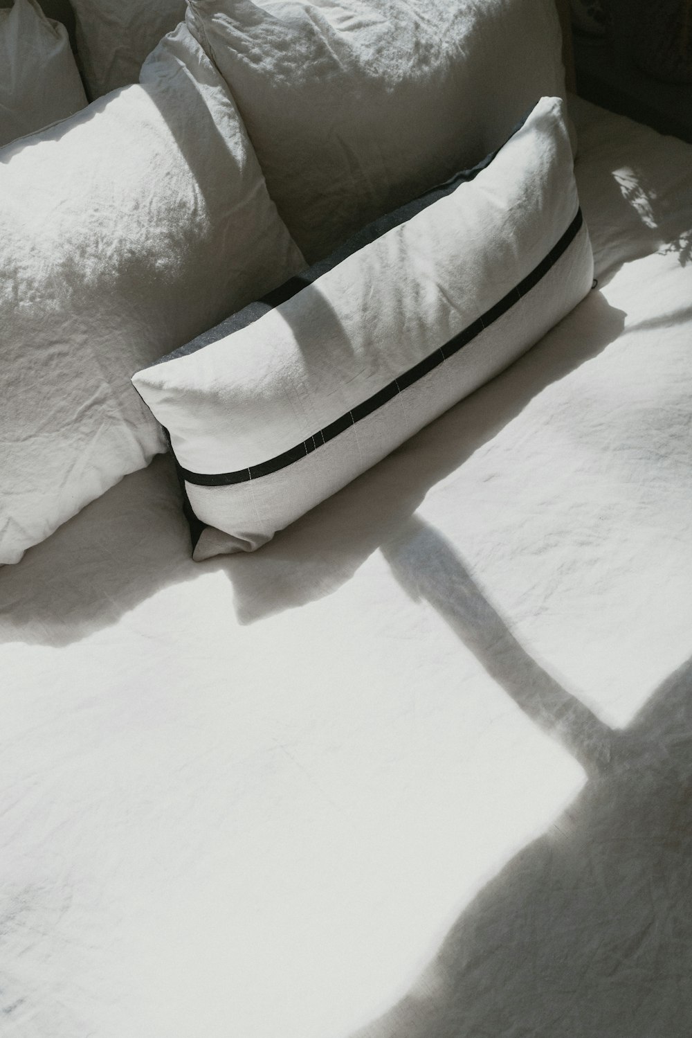 almohada blanca y marrón sobre cama blanca