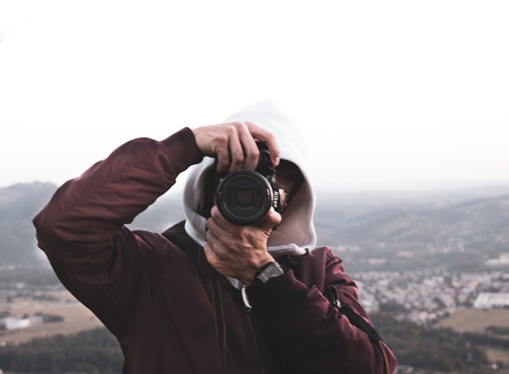 man in black jacket holding black dslr camera