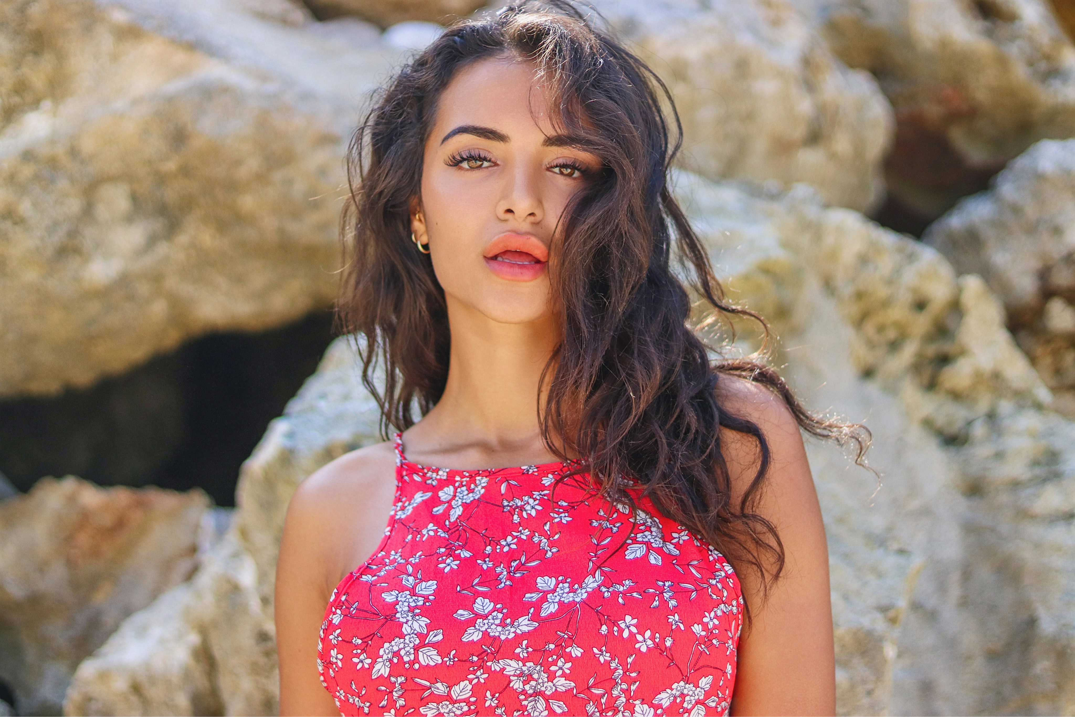 Girl in a red dress in front of beach rocks