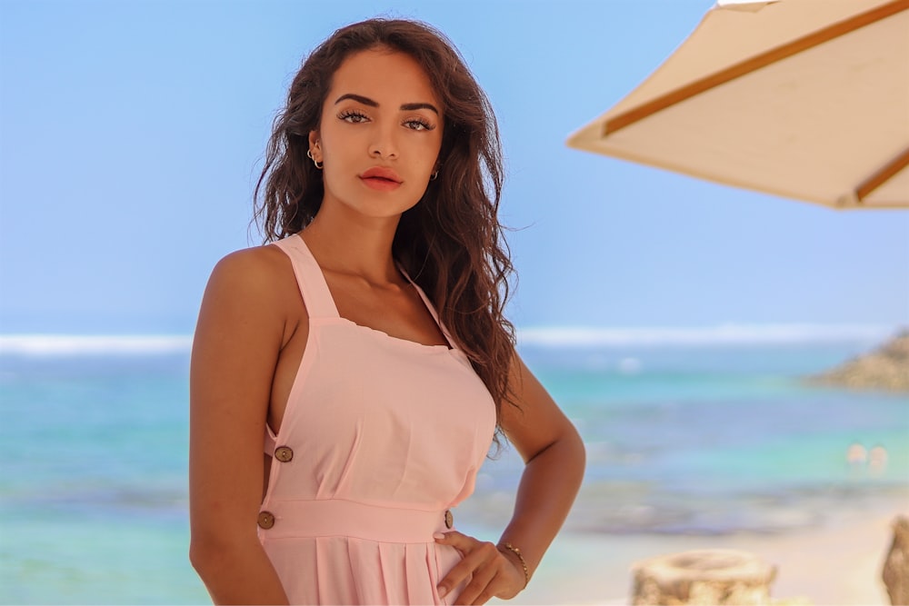 woman in pink spaghetti strap top standing on beach during daytime